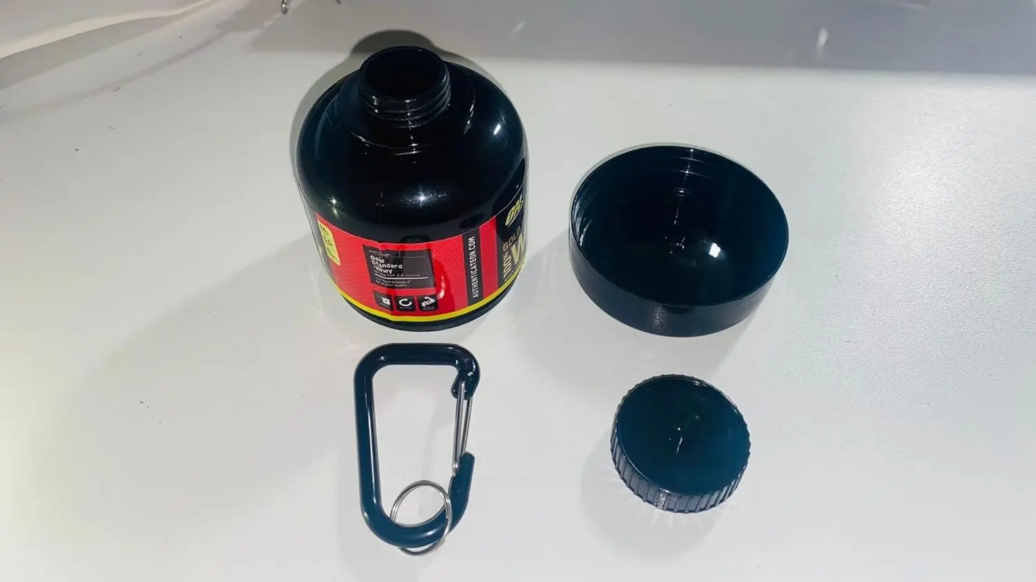 This black, portable protein powder container with a keychain and funnel is perfect for carrying pre-workout supplements to the gym or while traveling for fitness.