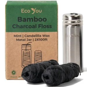 Two spools of bamboo charcoal dental floss refills with organic mint flavoring and plant-based candelilla wax, next to a reusable stainless steel container.