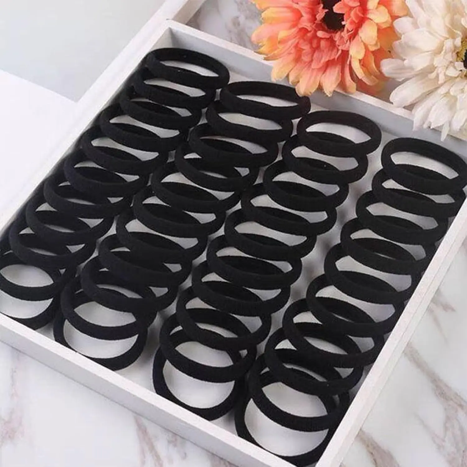 This image displays a collection of 200 black elastic hair ties in two sizes, perfect for creating various hairstyles for women and girls at home, in the gym, while traveling, or in a salon.