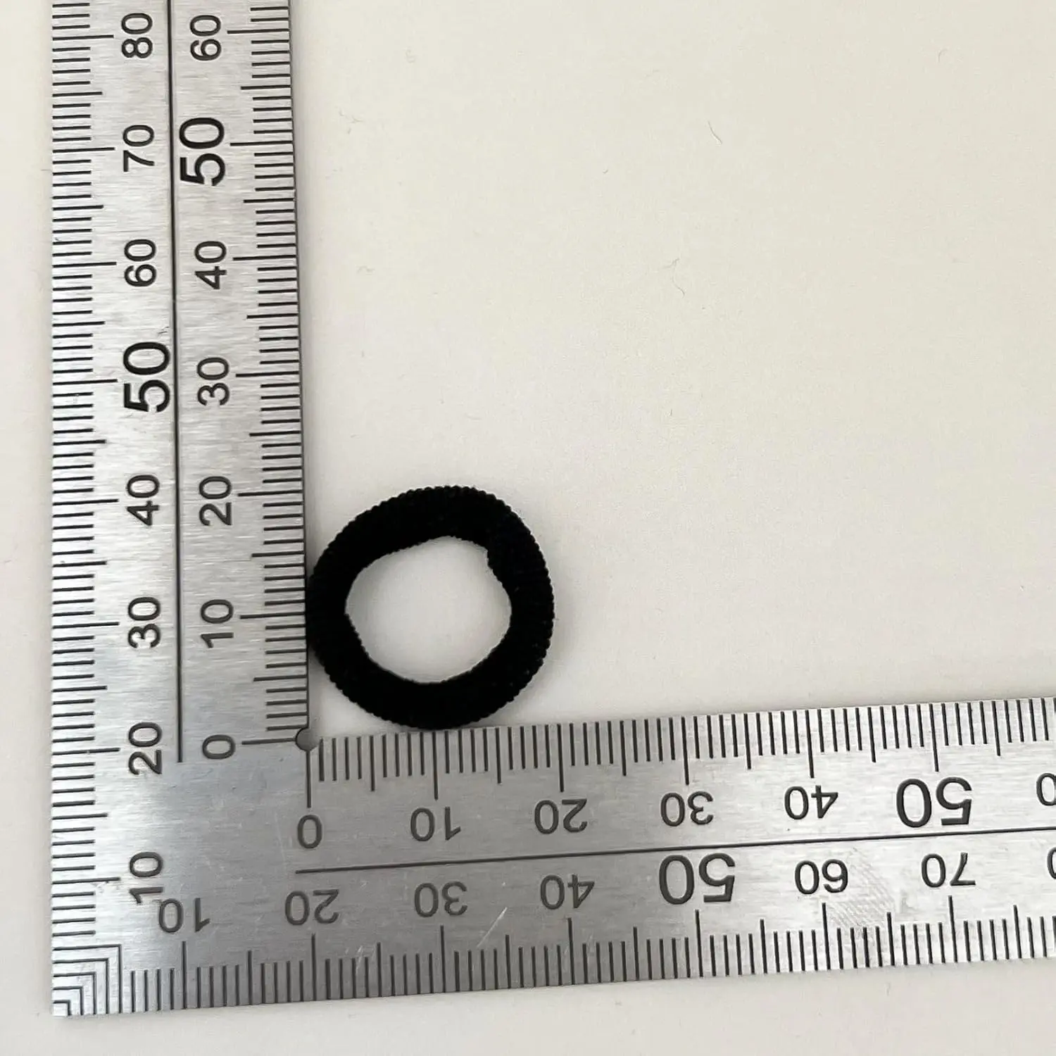 This image displays a collection of 200 black elastic hair ties in two sizes, perfect for creating various hairstyles for women and girls at home, in the gym, while traveling, or in a salon.