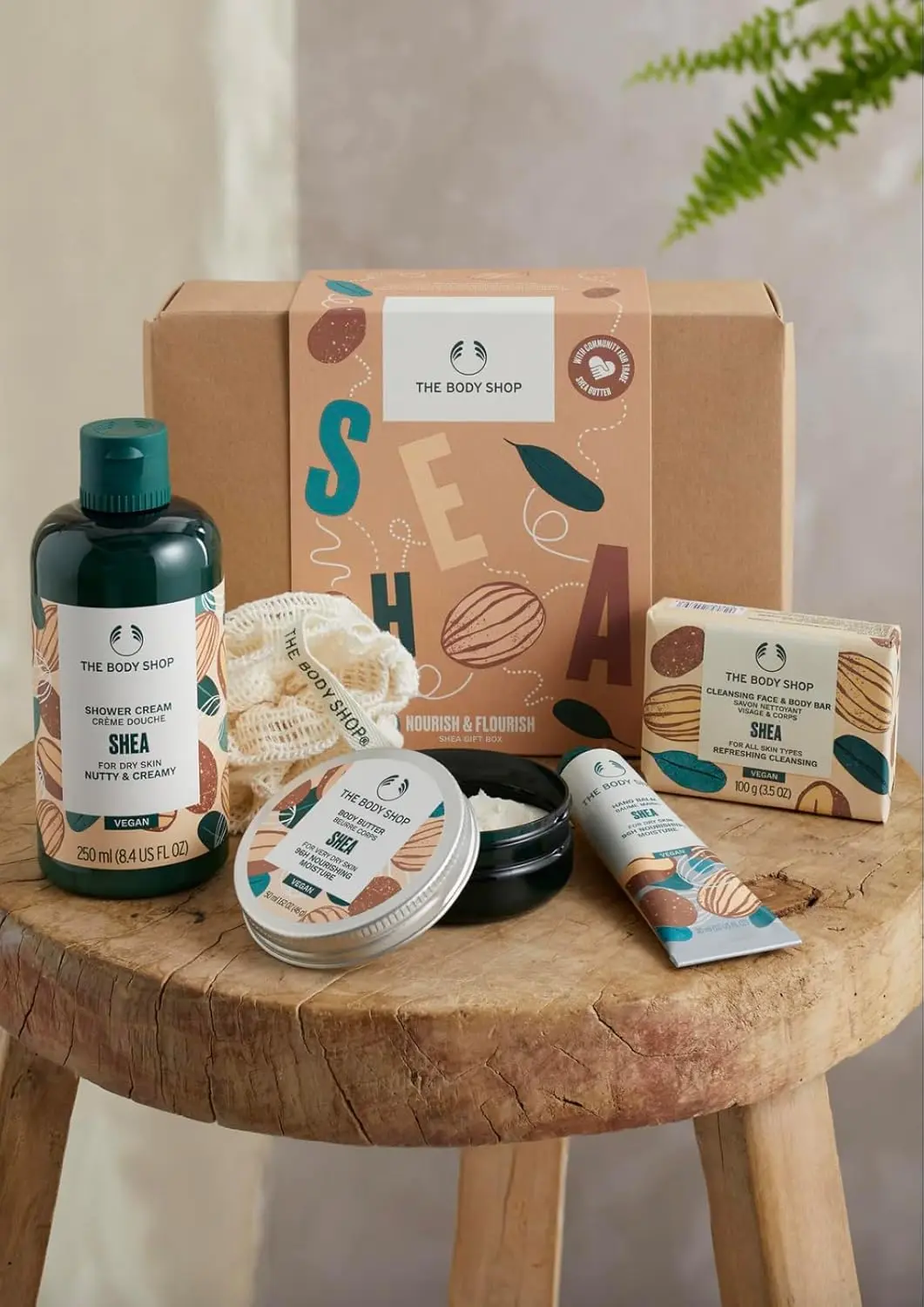 The Body Shop Shea Gift Set includes Shea Shower Cream, Body Butter, Hand Balm, Soap, and a Ramie Bath Flower for cleansing, nourishing, and pampering dry skin.
