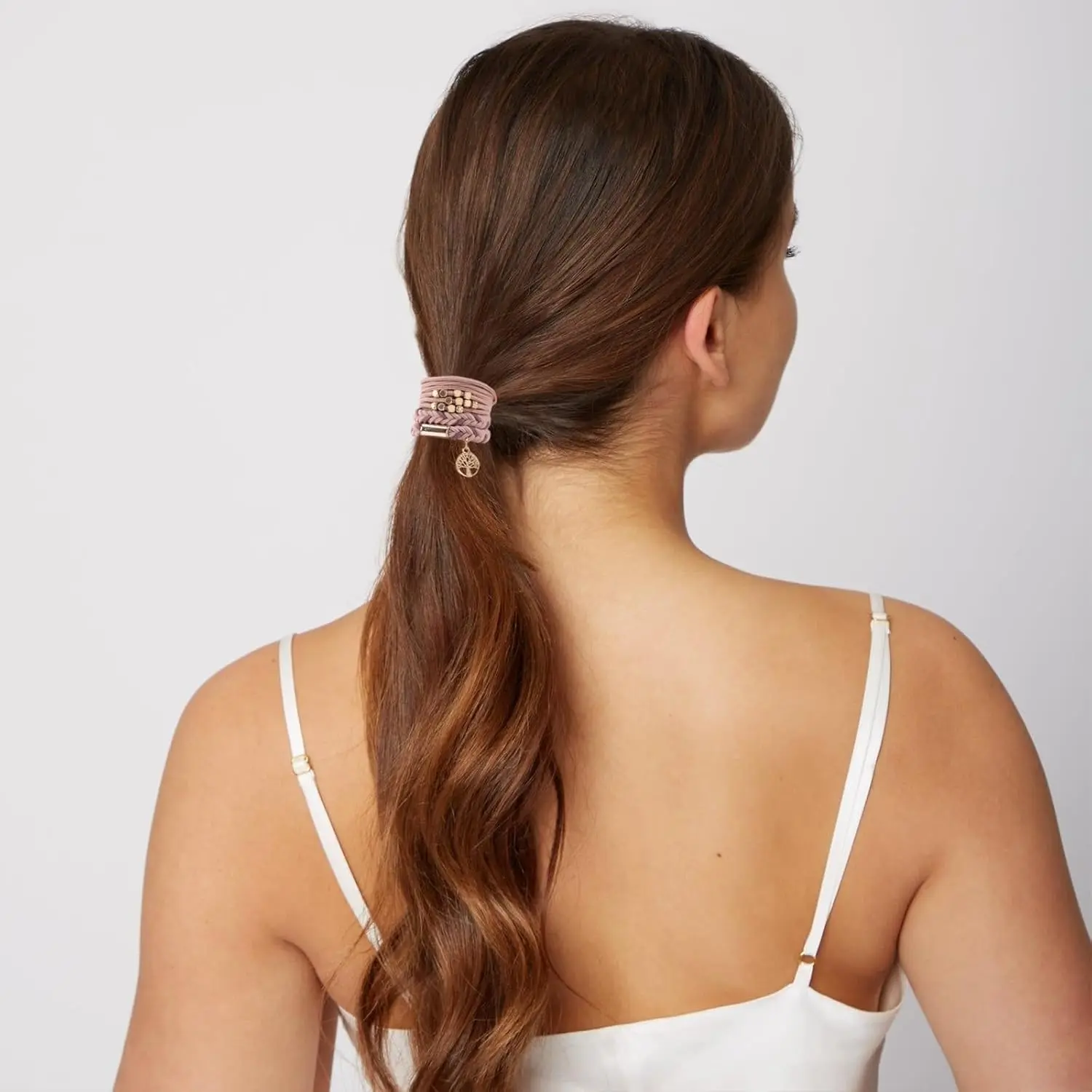 A set of ten pink boho hair tie bracelets with five different braided styles, designed to be gentle on hair and worn as stylish wrist accessories.