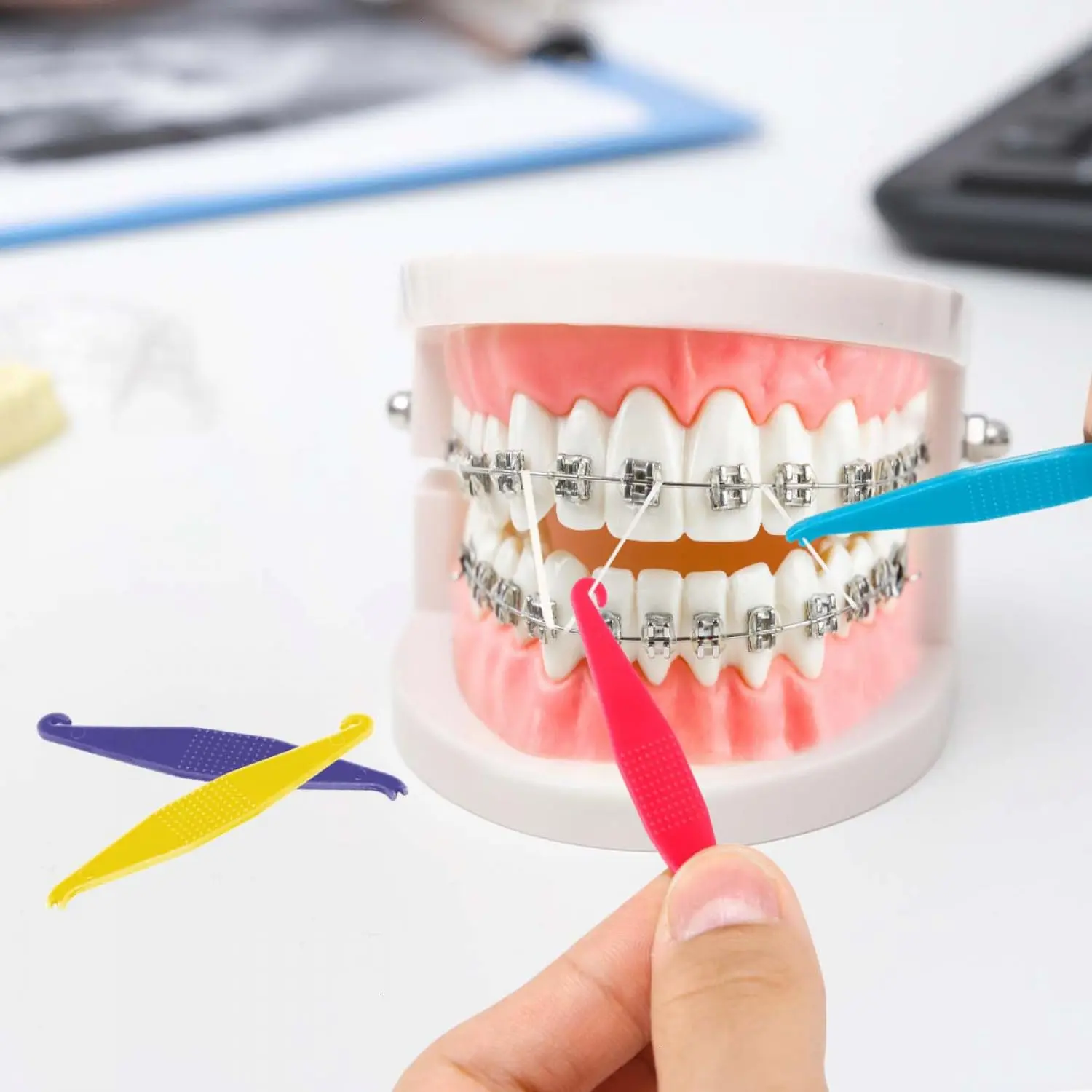 This set of 50 colorful dental elastic band placers are made of durable plastic and feature a 2-in-1 design for easy placement and removal of orthodontic brace bands.