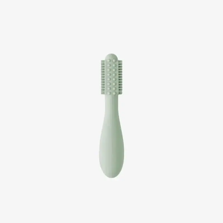 Sage-colored silicone baby toothbrush designed for infants 3+ months with an easy-grip handle and sensory bumps for early oral care.