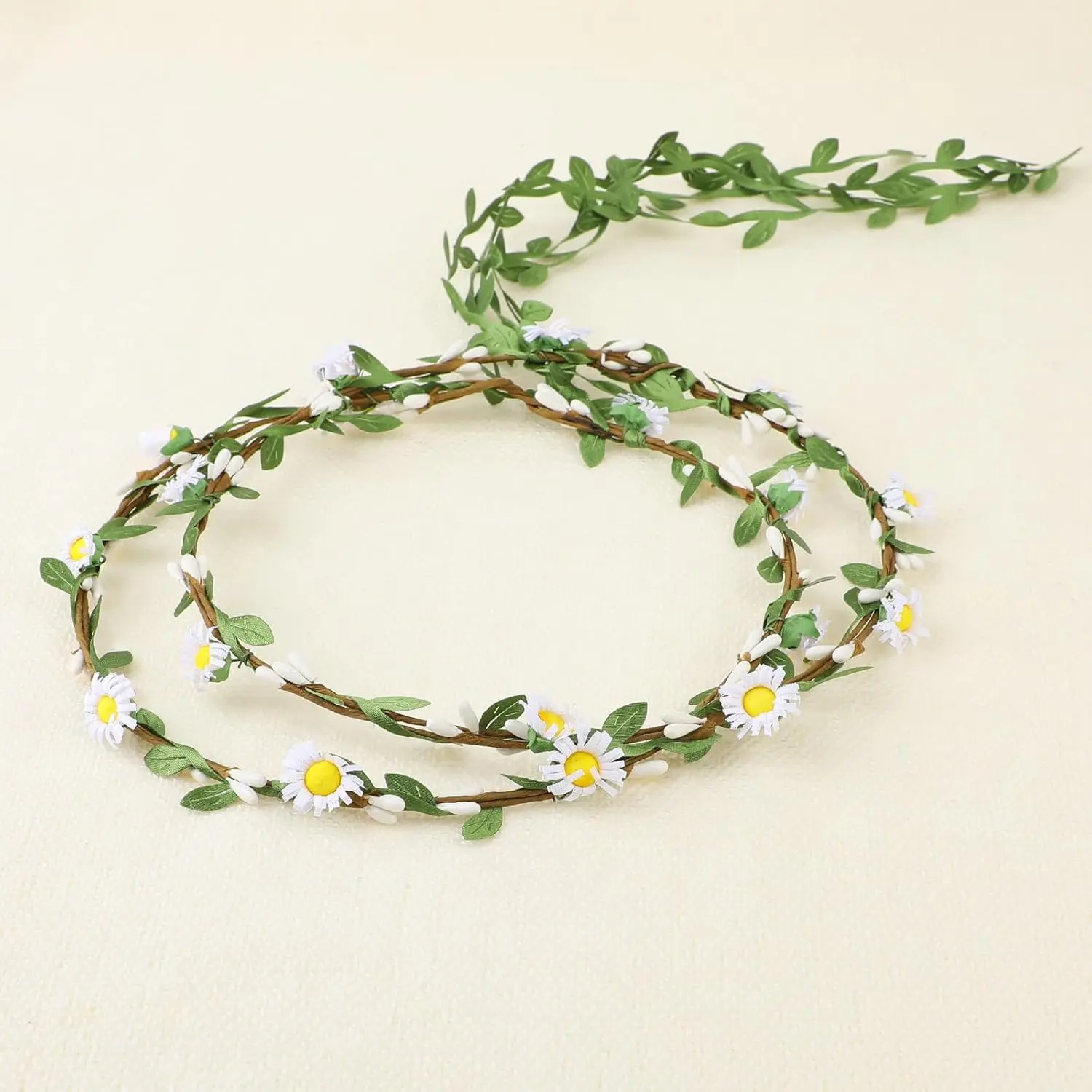 Two handmade flower crown headbands with artificial daisies, silk flowers, and green leaves, perfect for weddings and adding a bohemian touch to any hairstyle.