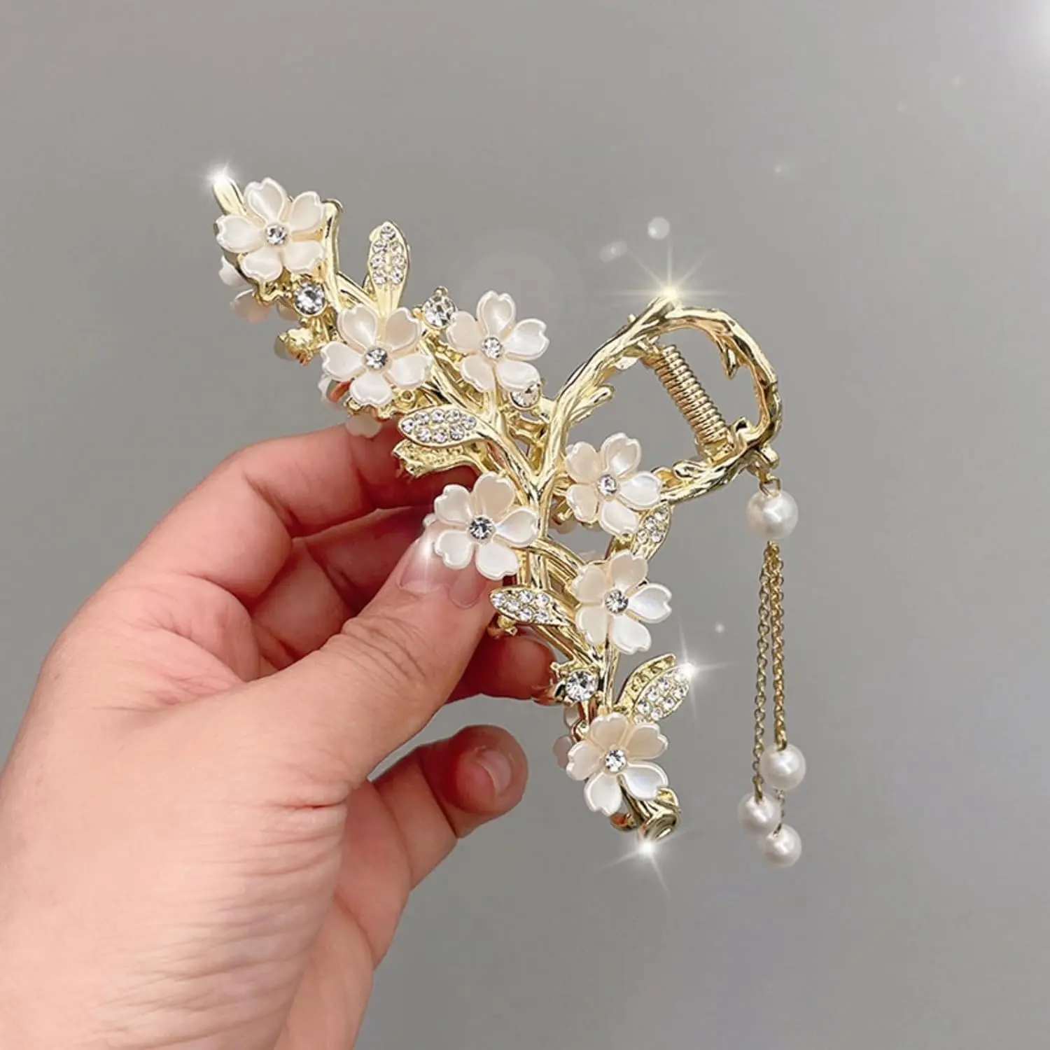 A gold flower hair clip with pearl and rhinestone tassel is a chic styling accessory.
