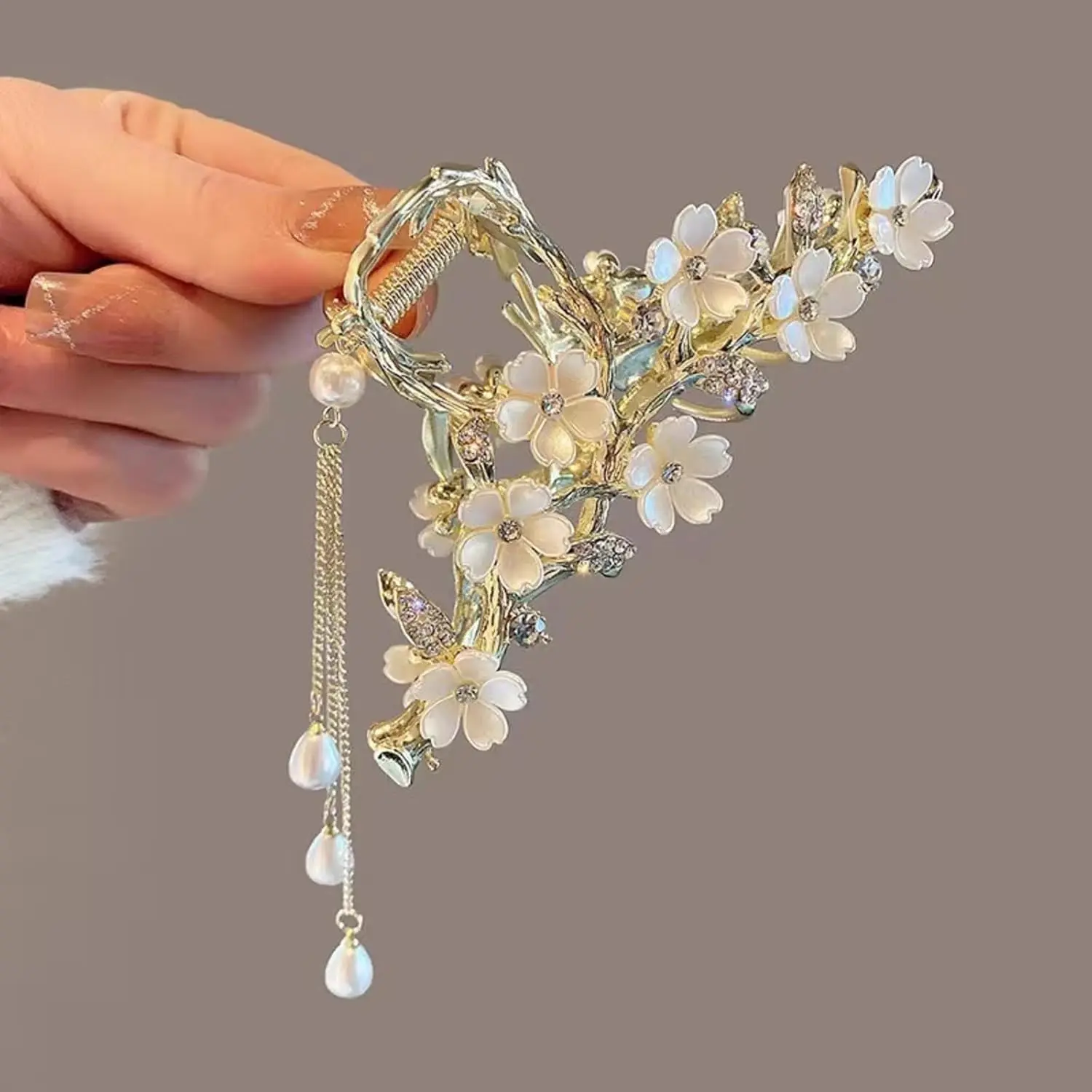 A gold flower hair clip with pearl and rhinestone tassel is a chic styling accessory.