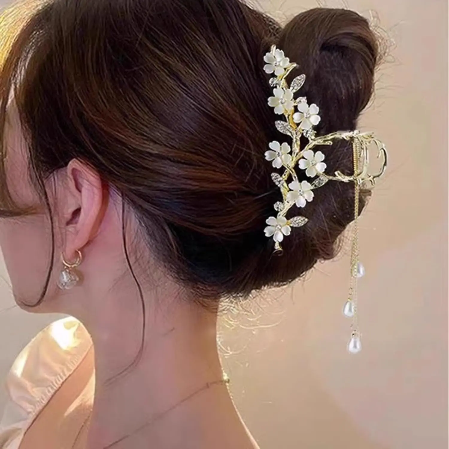 A gold flower hair clip with pearl and rhinestone tassel is a chic styling accessory.
