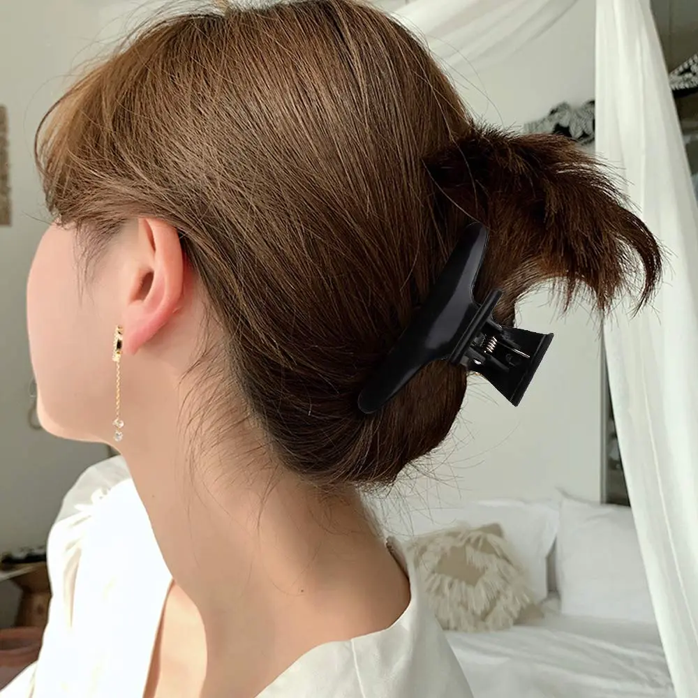 This image shows a 12 pack of black butterfly hair clips designed for styling, sectioning and coloring hair in a salon or at home, featuring a strong grip and durable plastic construction.