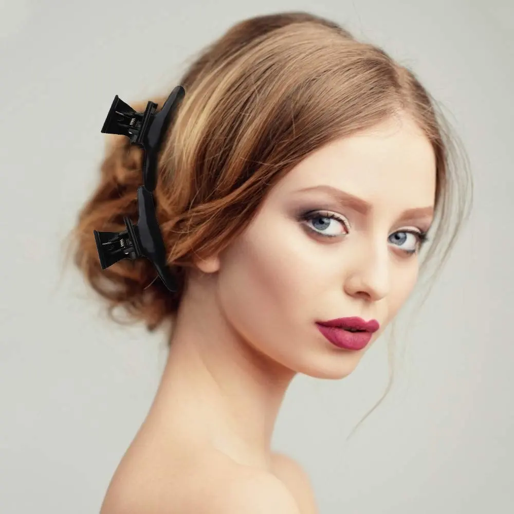 This image shows a 12 pack of black butterfly hair clips designed for styling, sectioning and coloring hair in a salon or at home, featuring a strong grip and durable plastic construction.