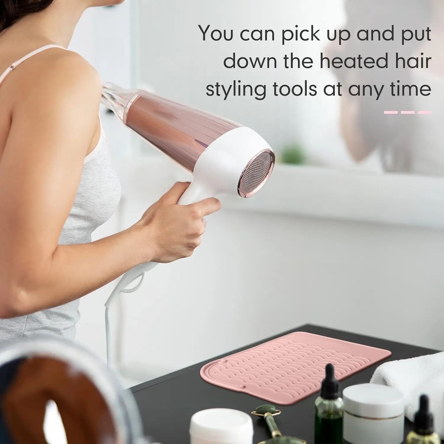 Pink silicone heat resistant mat safely holds hot curling iron and hair straightener, protecting surfaces from heat damage with its non-slip wave design and convenient hanging strap.