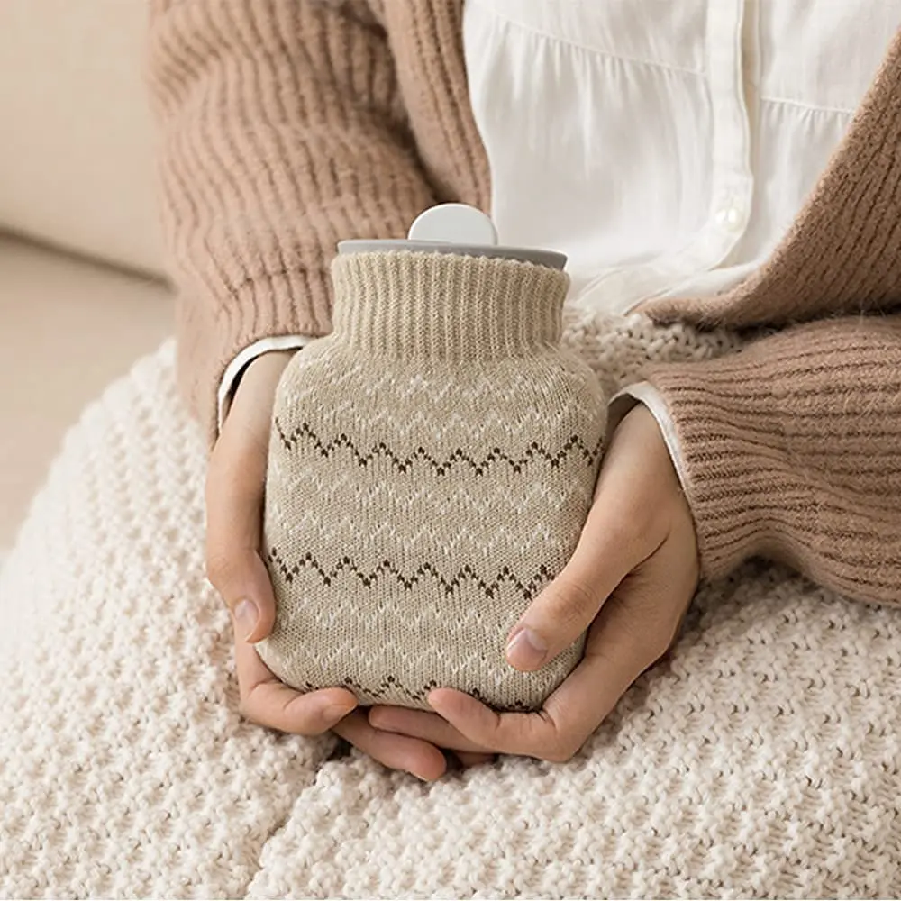 This small grey hot water bottle with a soft knit cover provides comforting warmth for cold feet, cramps, or period pain, and is microwave-safe for easy heating.