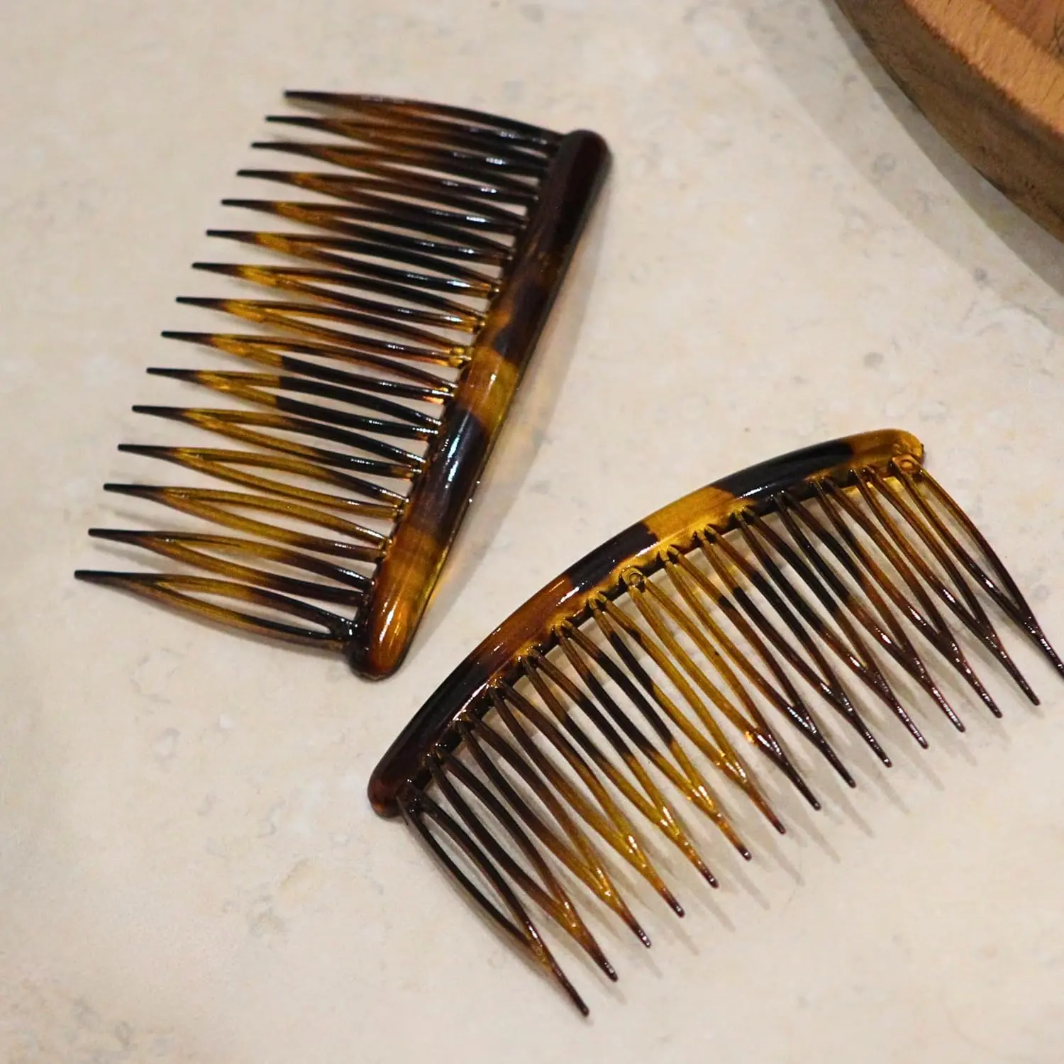 This image shows a pack of two tortoiseshell Manicare side combs designed with a French style for a strong, comfortable hold on all hair types.
