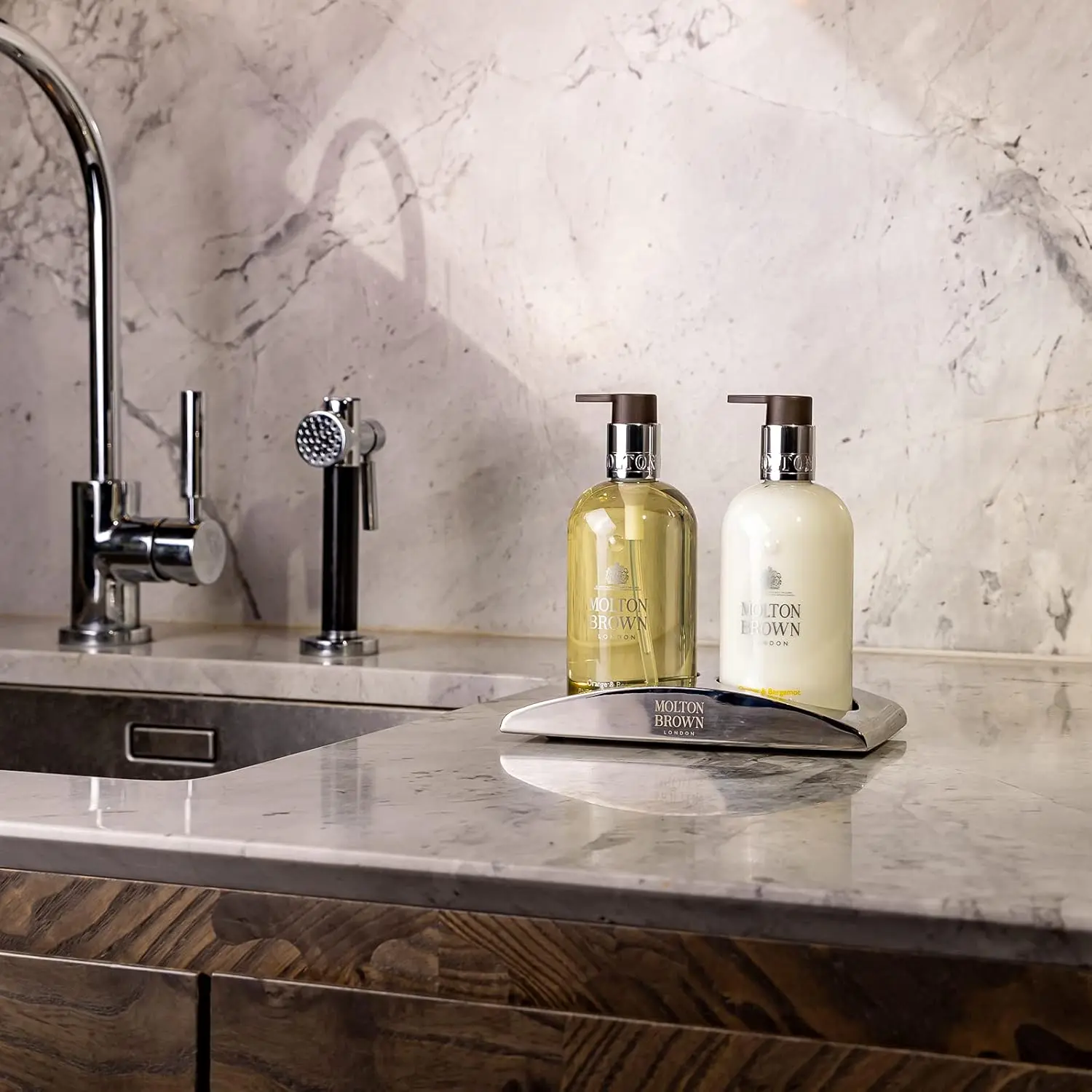 Sleek stainless steel Molton Brown Elemental Arc hand wash holder designed to elegantly display hand wash and lotion bottles in your bathroom or kitchen.