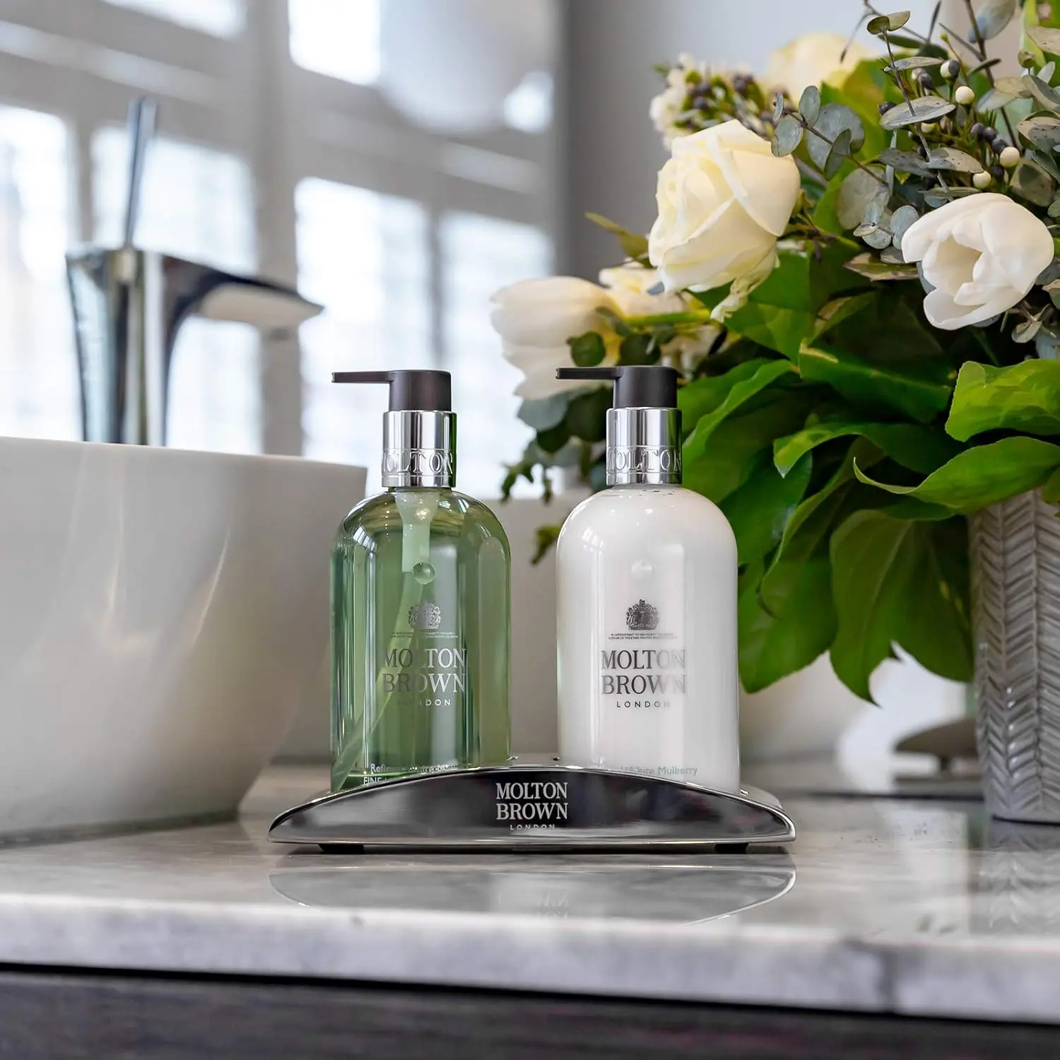 Sleek stainless steel Molton Brown Elemental Arc hand wash holder designed to elegantly display hand wash and lotion bottles in your bathroom or kitchen.