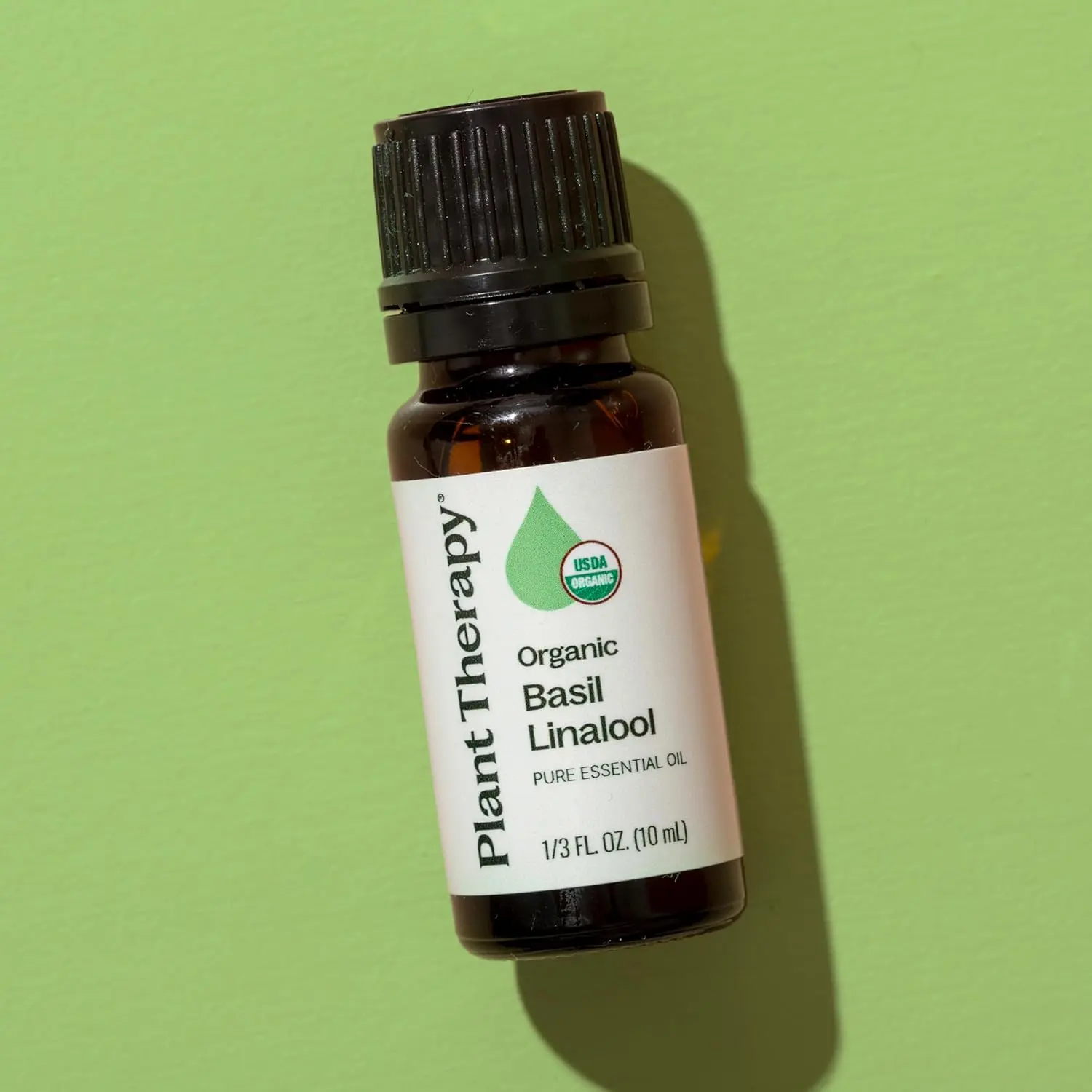 Plant Therapy organic basil linalool essential oil in a small amber bottle, steam distilled from basil leaves for a sweet, herbaceous, and uplifting aroma.