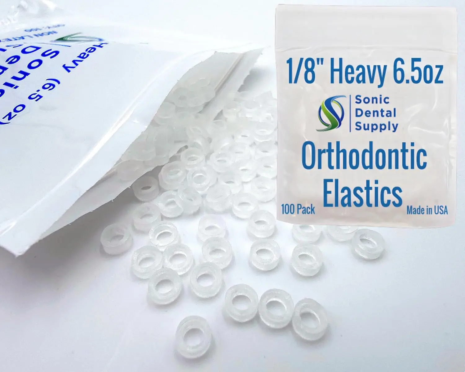 A close-up shows a small pile of clear, latex-free orthodontic elastic rubber bands, size 3/16 inch with light force, designed for braces and other uses.