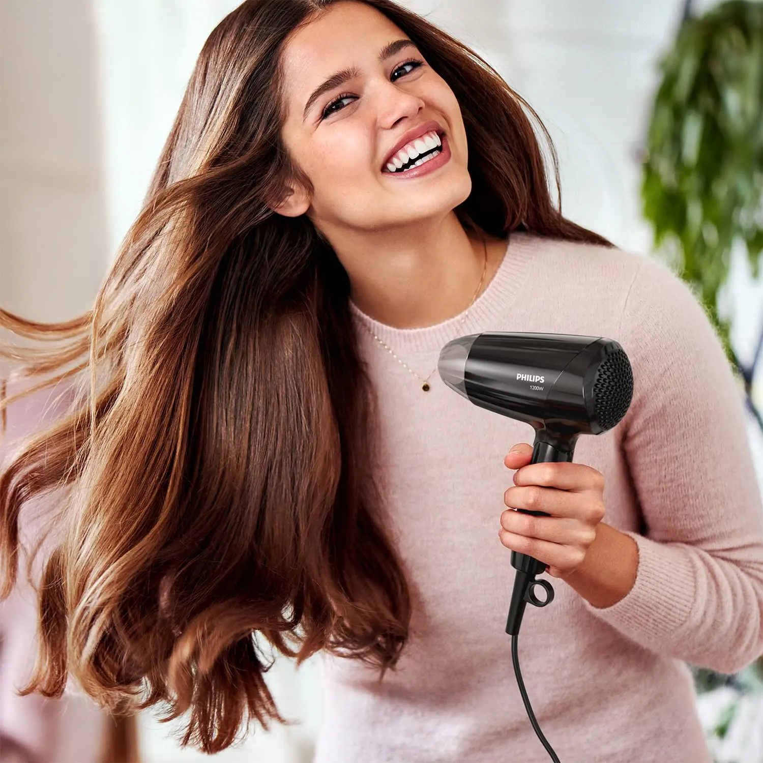 Black Philips Essential Care BHC010/10 hair dryer with ThermoProtect setting and foldable handle, offering 1200W power for quick, gentle, and shiny hair drying with three preset levels and a styling nozzle.