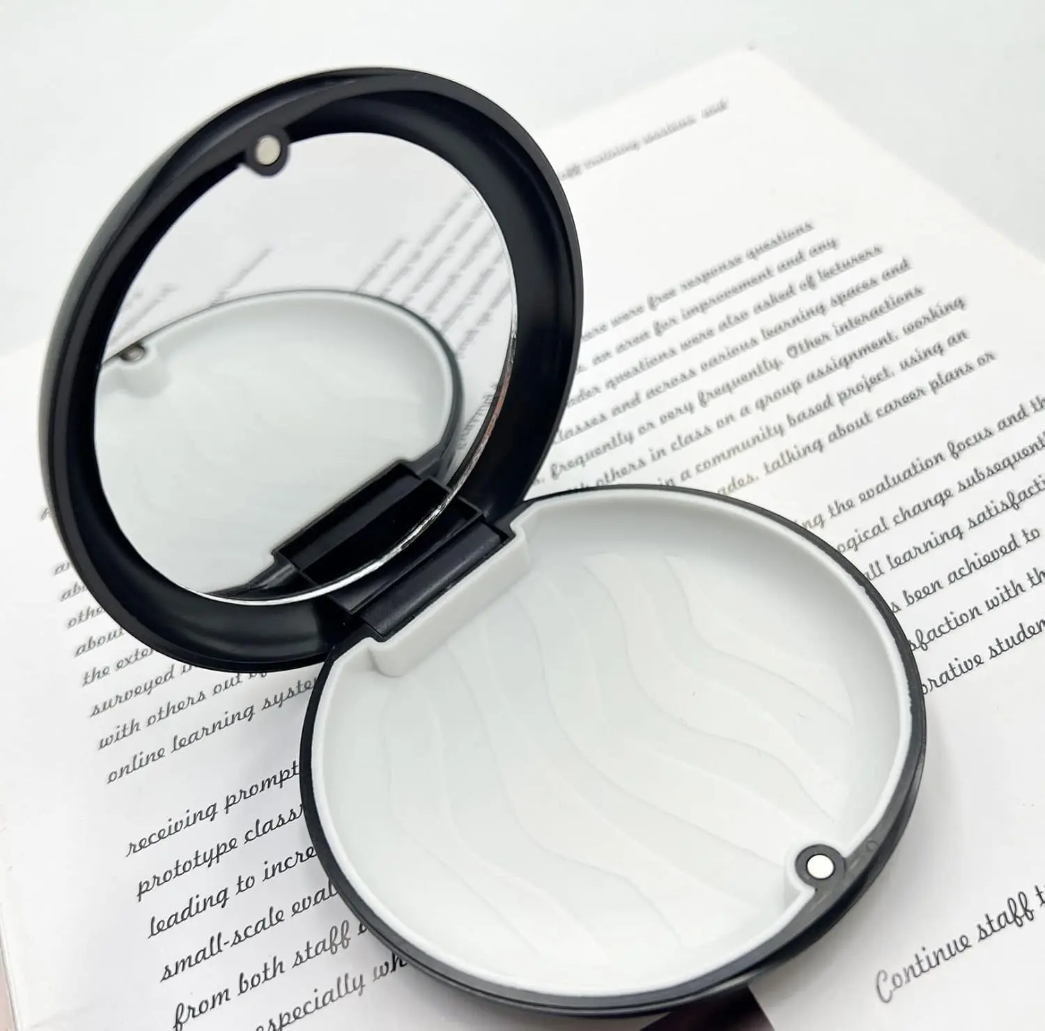 Black orthodontic retainer case with inlaid mirror and magnetic closure for easy aligner removal.