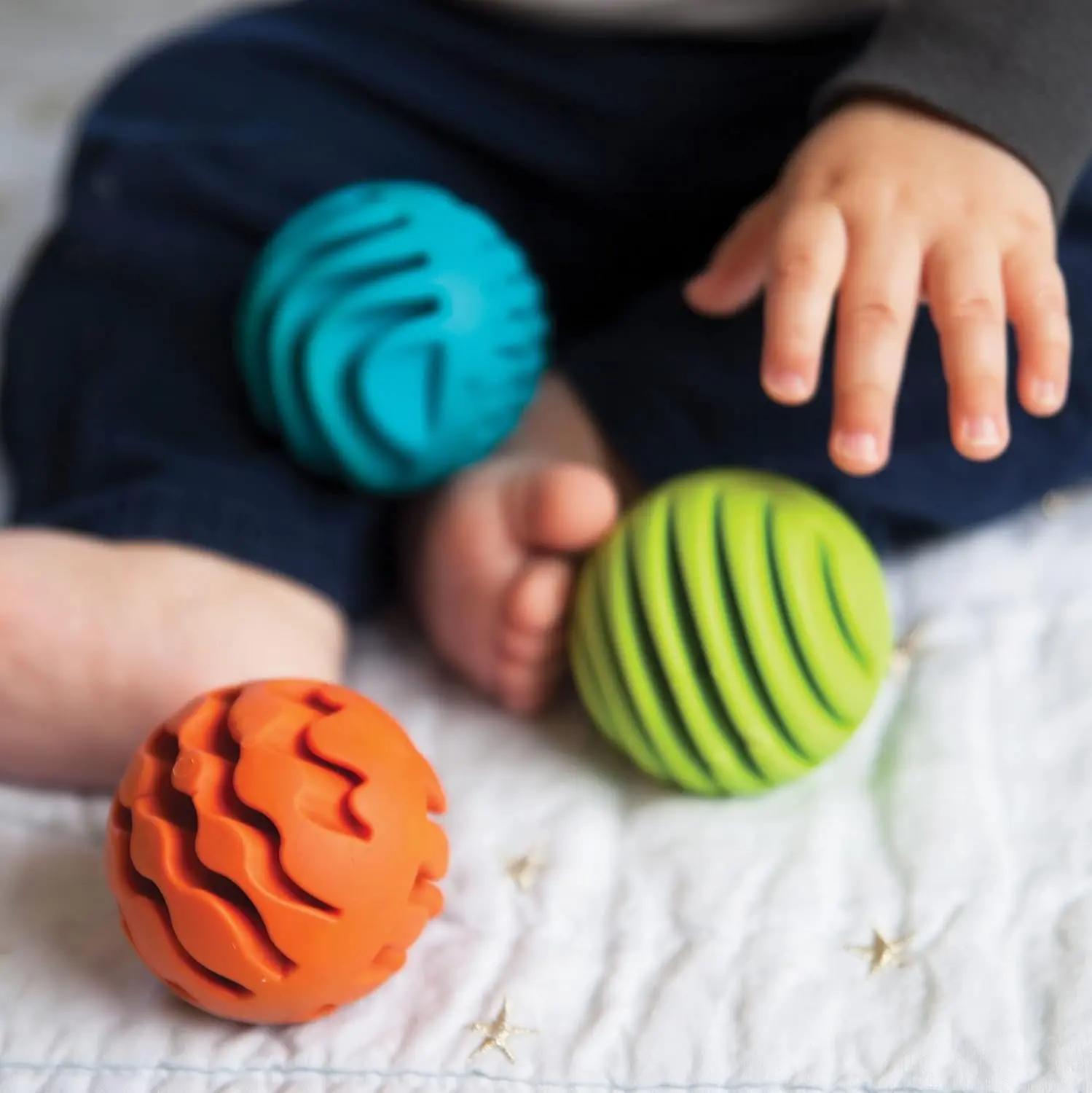 Three textured silicone sensory rollers with chimes inside, designed for infants 6 months and older to encourage sensory exploration and tactile learning.