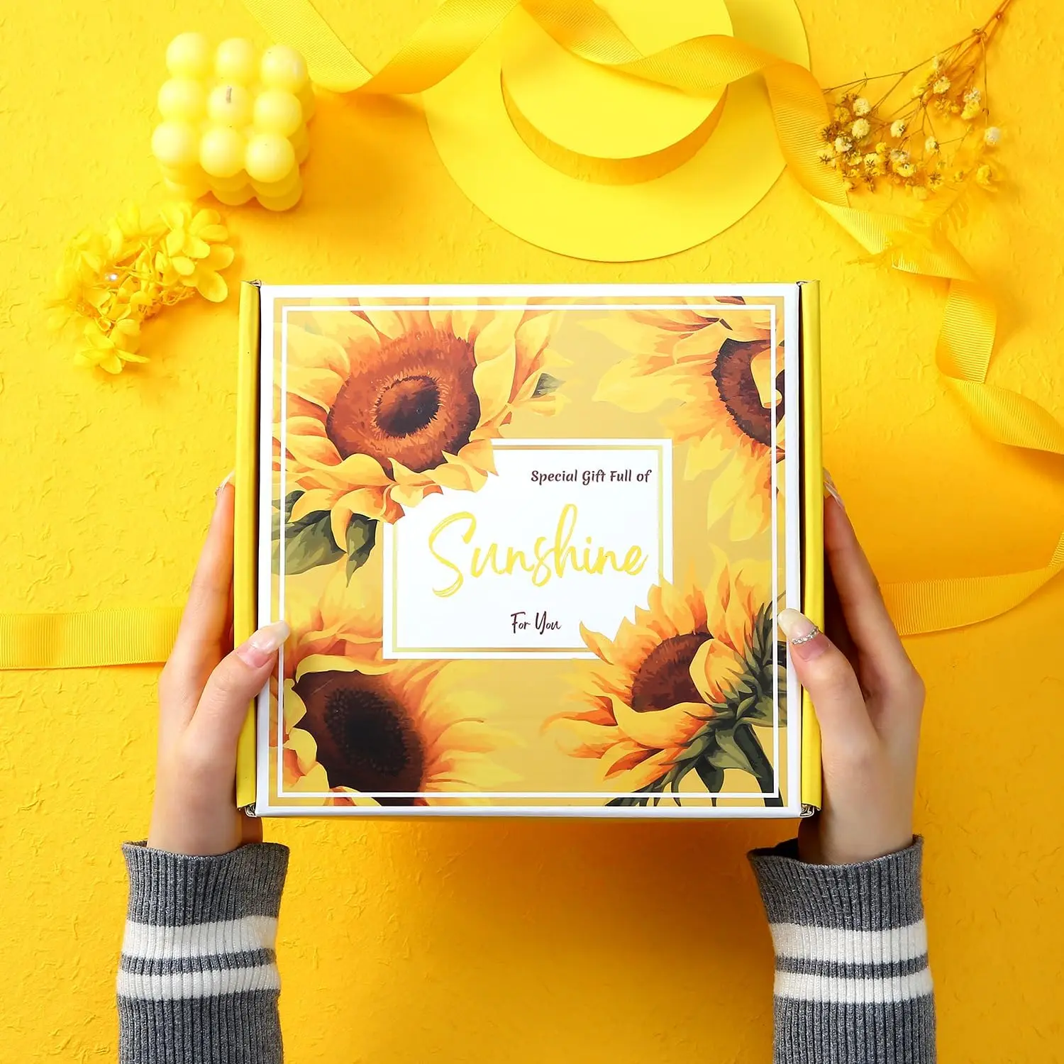 This spa gift set for women includes a sunflower-themed bath bomb, scented candle, tumbler, jewelry, and other self-care items in a beautifully packaged gift box.