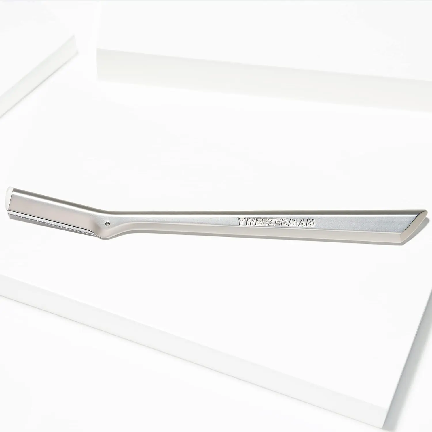 Silver Tweezerman facial razor dermaplaner for removing peach fuzz and exfoliating skin, comes with three replacement blades.
